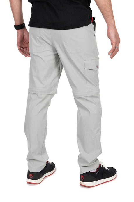 Hombre mostrando pantalón desmontable gris claro de Fox Rage, ideal para pesca, con bolsillos seguros y diseño cómodo.